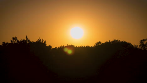 Time-lapse-of-a-sunset-behind-a-silhouetted-treeline