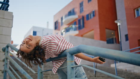 happy woman earphones listening music leaning on street stairs railings.