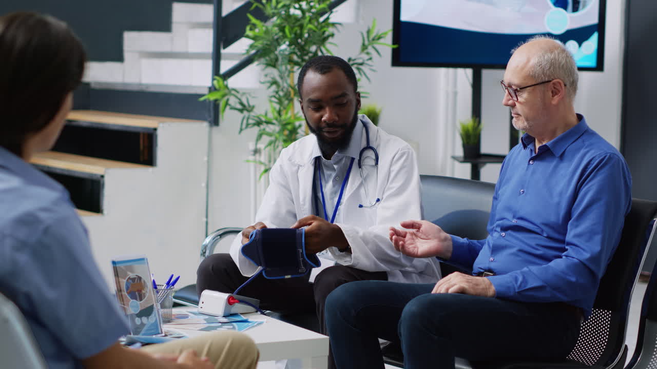 Doctor checking patient's blood pressure during medical exam in hospital waiting room