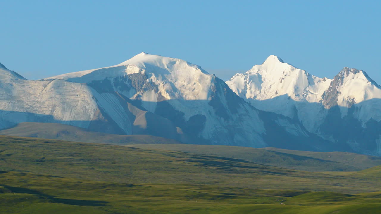 Malebný pohled na zasněžené vrcholky pohoří Ťan-šan přes údolí Sary Jaz v Kyrgyzstánu. Široký záběr dronem