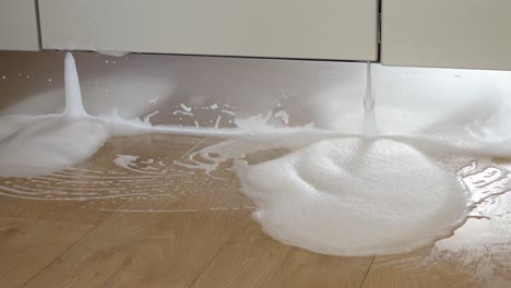 a kitchen floor with foam from a leaky dishwasher