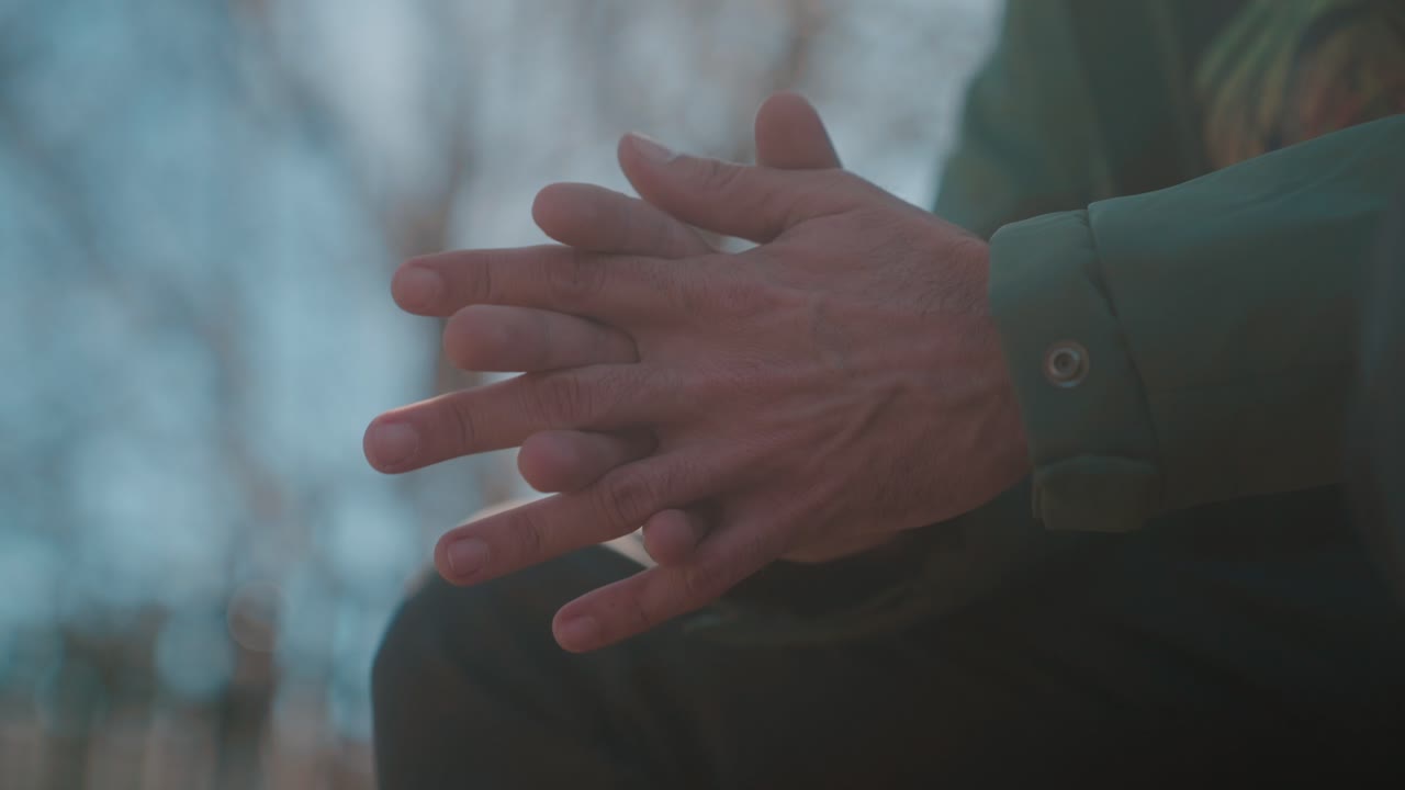 Man gesturing with hands in conversation outdoors during sunset, close-up shot