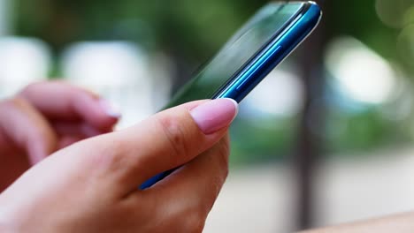 a woman is sitting in a cafe with a smartphone in her hands with a green screen mockup. the girl browses the internet, watches content, videos, blogs.