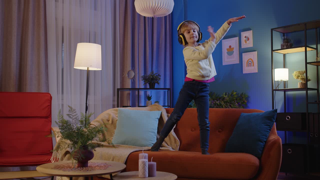 niña feliz niño con auriculares bailando moviéndose al ritmo mientras escucha música en casa sola