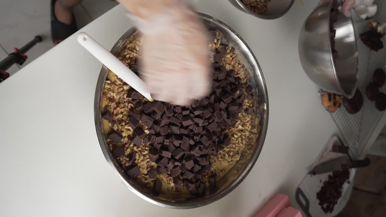 Pasticcere che versa cioccolato fondente tritato nell'impasto per biscotti