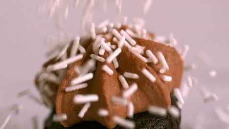 pink sprinkles falling onto chocolate cupcake