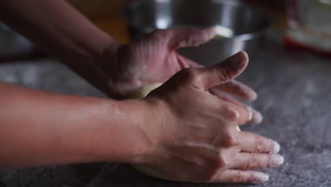 freshly mixed ball of dough being kneaded by hand on marble tabletop, filmed as closeup slow motion shot