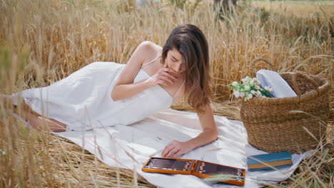 mujer inspirada dibujando la naturaleza acostada en el campo de espikelets. dama relajando la manta