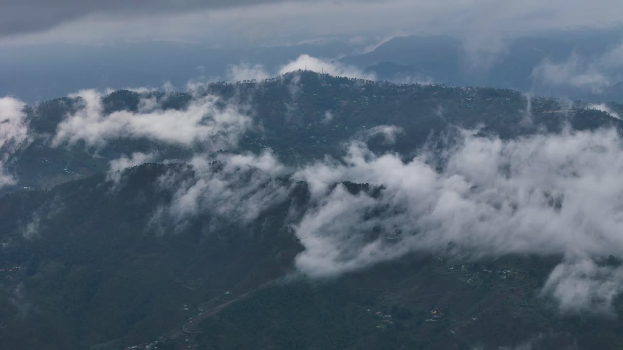 Aerial drone shot of a peaceful mountain morning where clouds float just above the forest canopy.