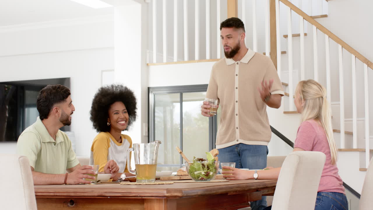 Group of young friends enjoying drinks and conversation around dining table
