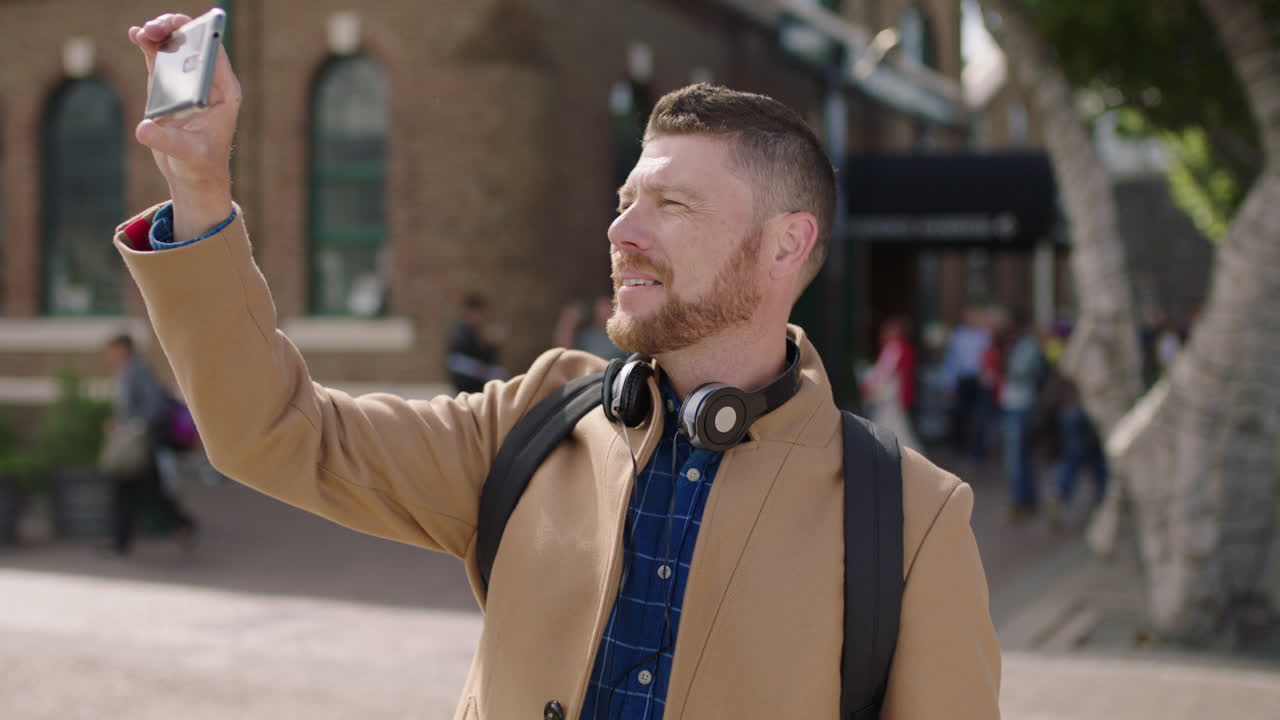 portrait of handsome caucasian man taking photo using smartphone in city smiling enjoying urban lifestyle