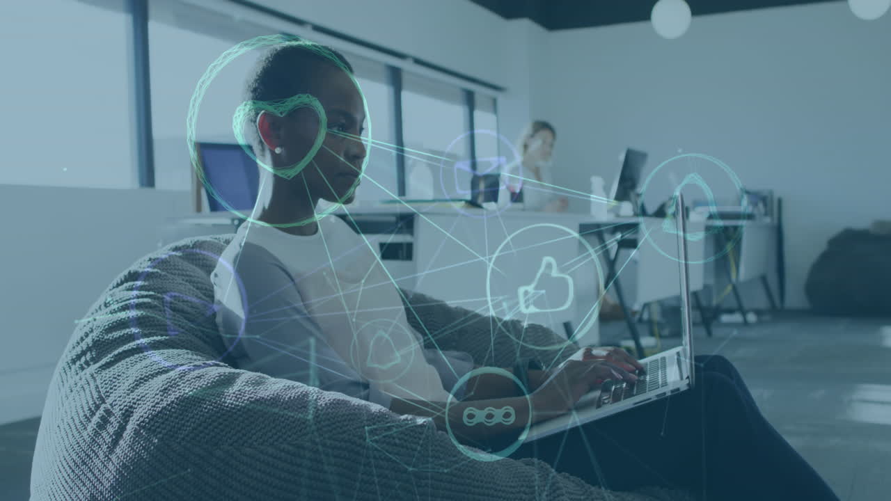 Animation of network of social media icons over african american woman using laptop in office