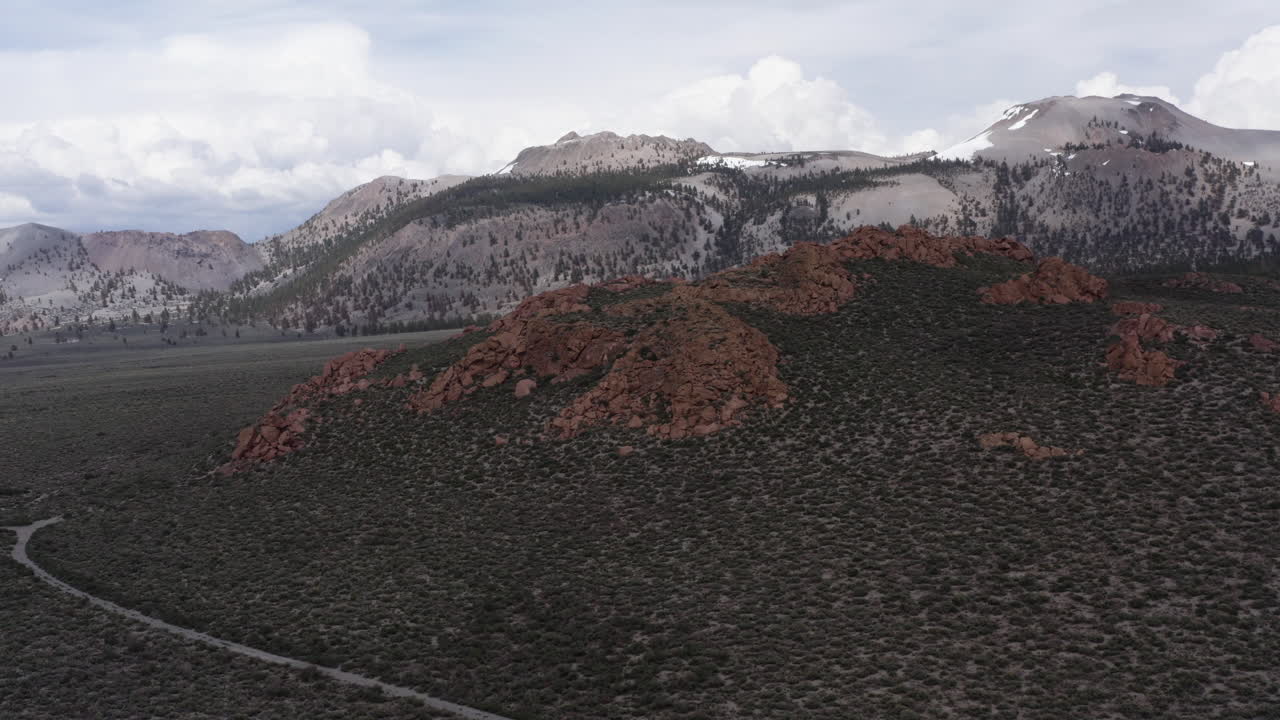 montañas cubiertas de nieve con escarpadas colinas rojas en primer plano, y el paisaje diverso de la sierra oriental