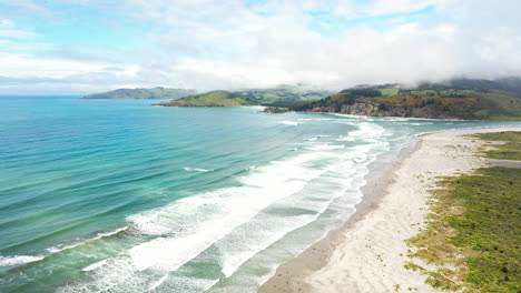 blue ocean waves of blueskin bay in warrington domain beach, new zealand, aerial view