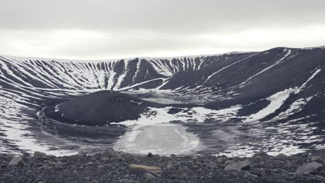 Reveal-of-Hverfjall-Volcano-crater-with-black-rock-and-snow,-Iceland