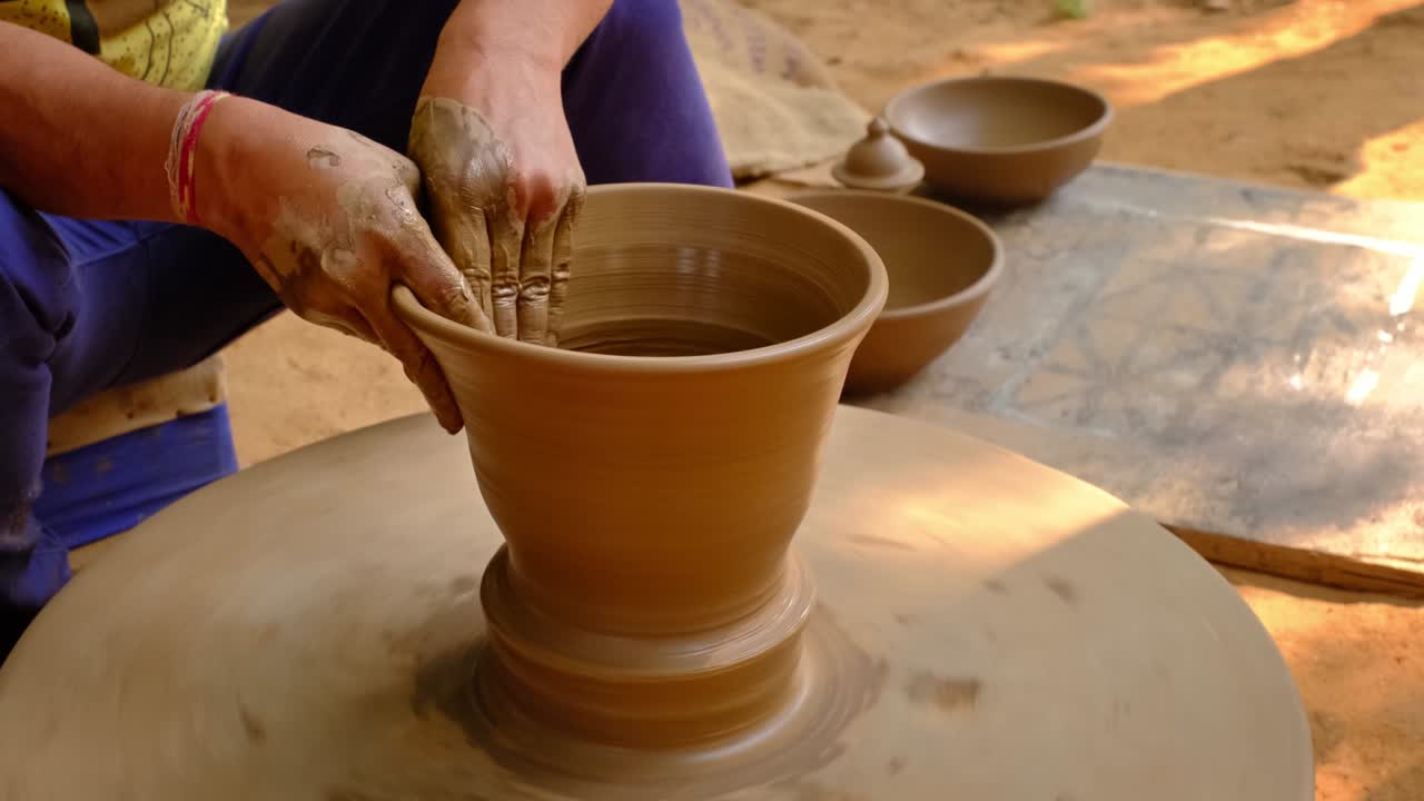 las manos hábiles del alfarero moldeando el barro en la rueda del alfarer y esculpindo jarras de barro. shilpagram, udaipur, rajasthan, india