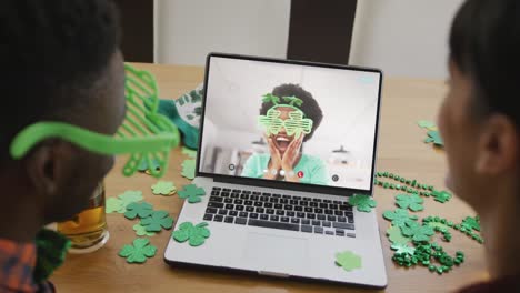 smiling african american woman wearing clover shape items on video call on laptop