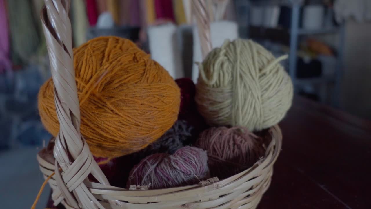 Slow orbiting shot of balls of yarn in a wooden wicker basket