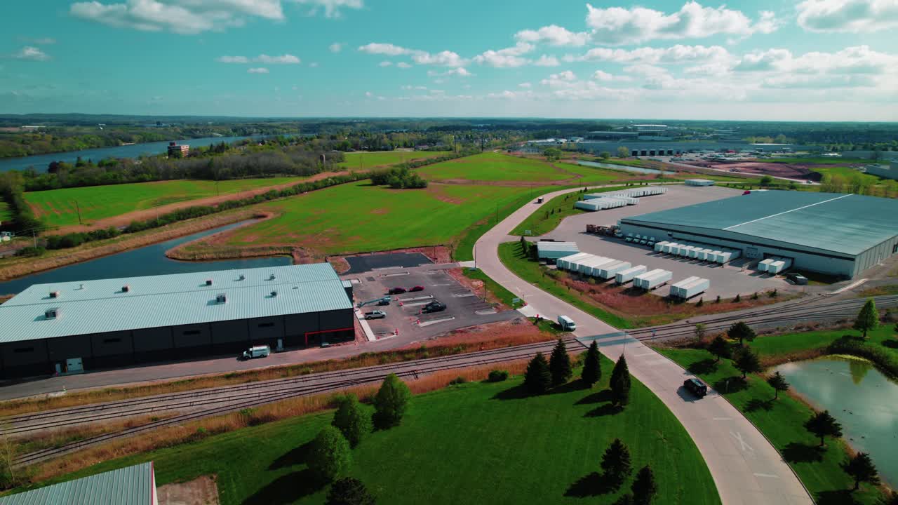 Smooth drone following a car across a North Wisconsin logistics hub surrounded by farmland—ideal for industrial and corporate projects