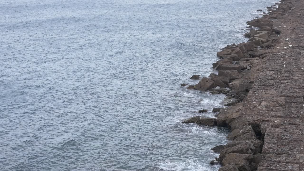 Detailed view of ocean waves breaking against a rocky breakwater off the coast of Melilla