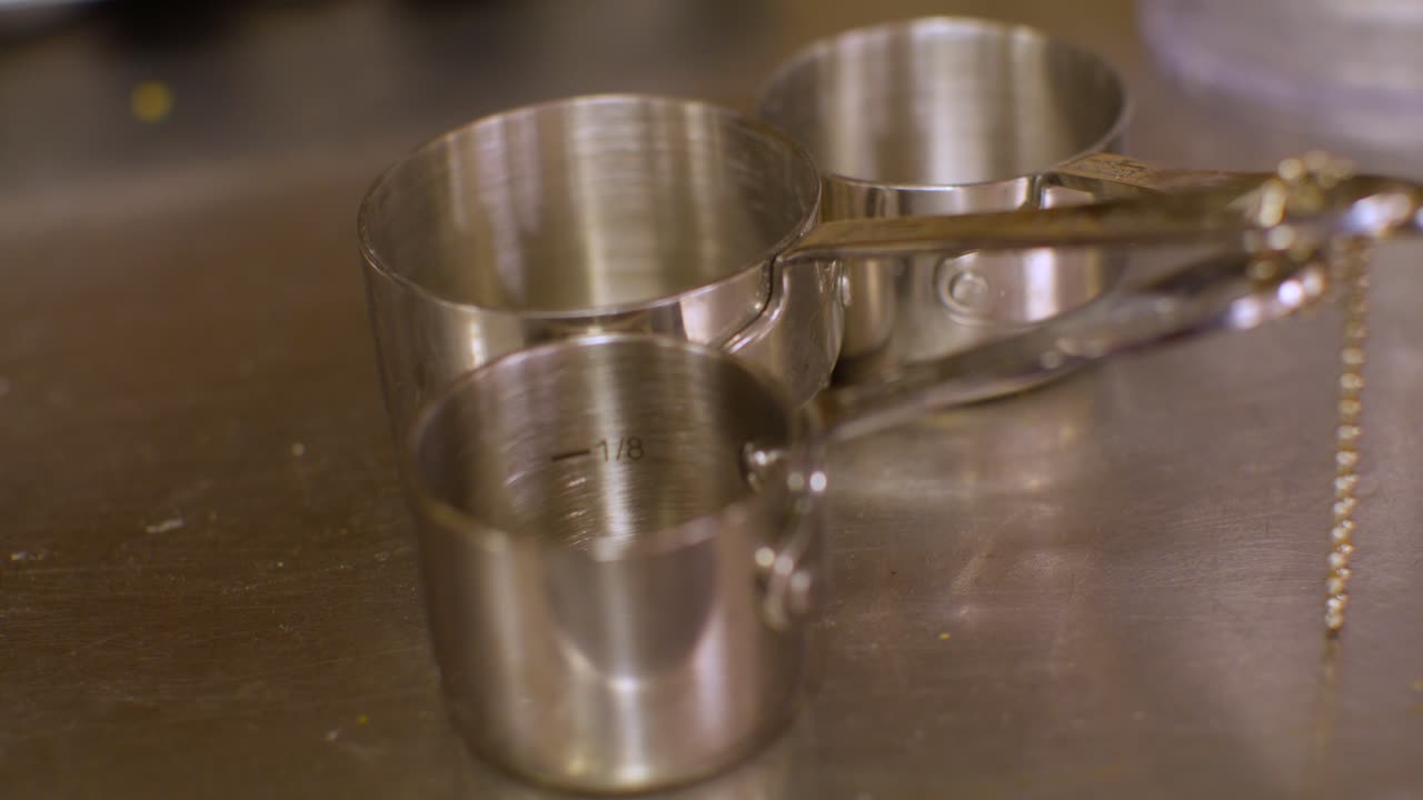 Three stainless steel measuring cups with stable video.