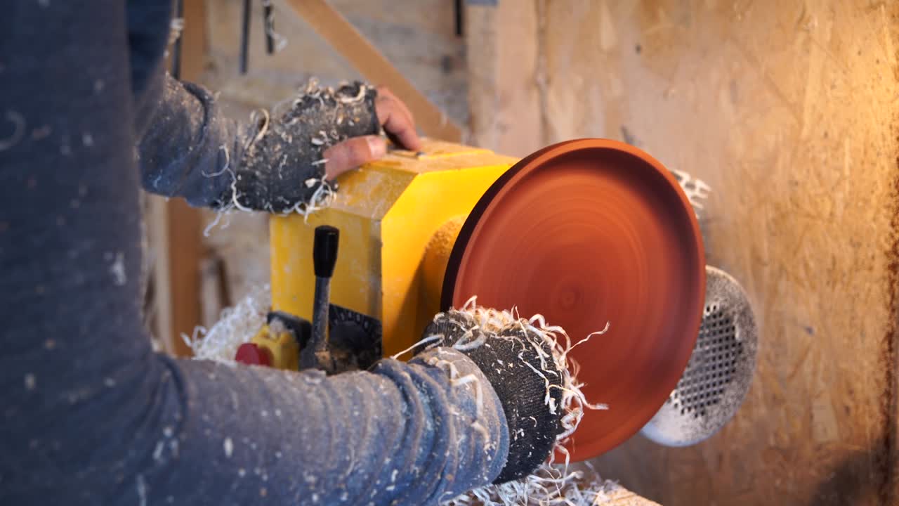 목공은 작업장에서 접시를 가지고 일합니다.