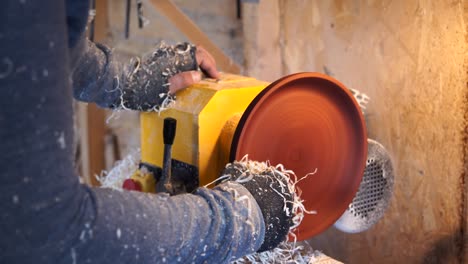 woodworker works with dish in workshop.