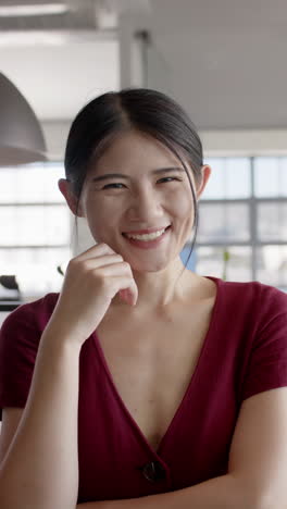 Vertical video of portrait of happy asian businesswoman smiling in office
