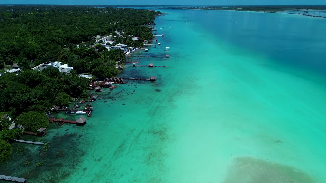 Drone aerial landscape of Bacalar town village lagoon lake with sandbar and hotel resort huts with jetty boardwalk wharf Mexico Central America vacation holidays