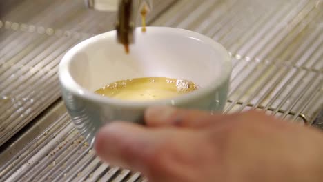 a barista pours coffee into a cup and then takes it away