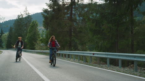 Couple-cycling-mountain-road-together-in-forest-landscape.-Tourists-riding-bike.