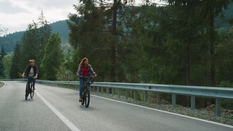 pareja en bicicleta por una carretera de montaña juntos en un paisaje forestal. turistas en bicicleta.