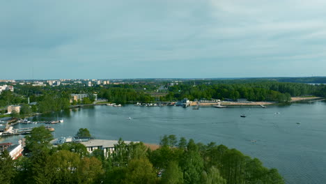 a panoramic view of ukiel lake, bordered by dense greenery and a developed urban area, under a clear sky