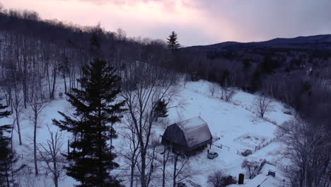 El-Dron-Orbita-Alrededor-Del-Granero-En-Las-Montañas-Nevadas-De-Vermont-Durante-La-Radiante-Puesta-De-Sol