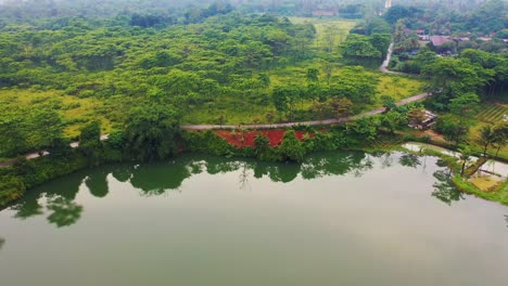 drone captures landscape in samoa after tropical cyclone showing calm lake bordered by dense forest muddy ground and light damage under cloudy sky reflecting slow recovery of natural environment