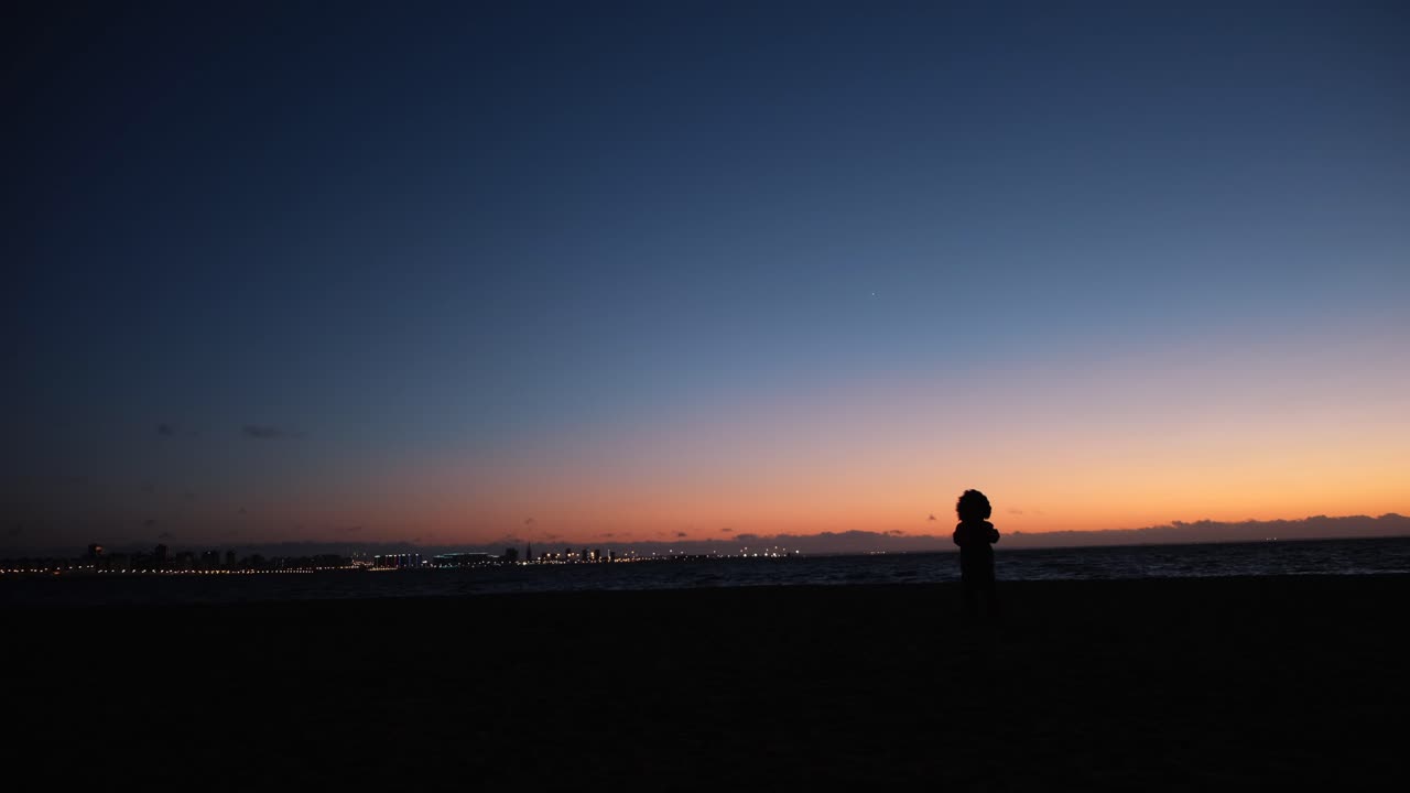 해가 지는 해변 에 있는 어린이 의 실루