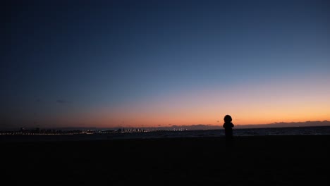 child silhouette on beach at sunset