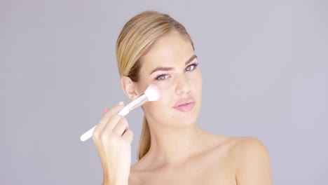 beautiful young female applying makeup on cheek