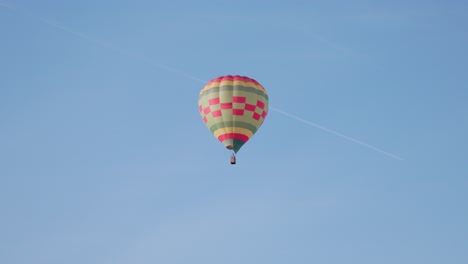 a single hot air balloon gracefully drifts through a clear blue sky, creating a serene scene at the canberra balloon spectacular.