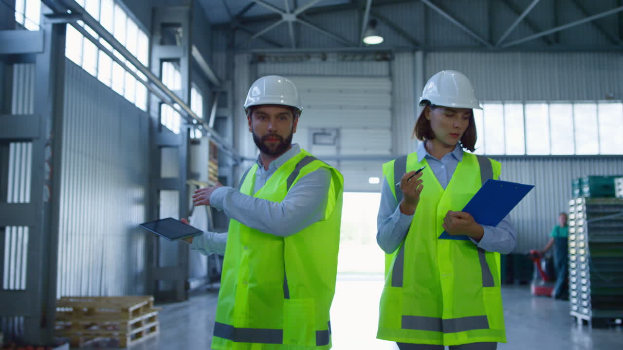 especialistas de almacenes discutiendo datos de tabletas inspeccionando el complejo de envío