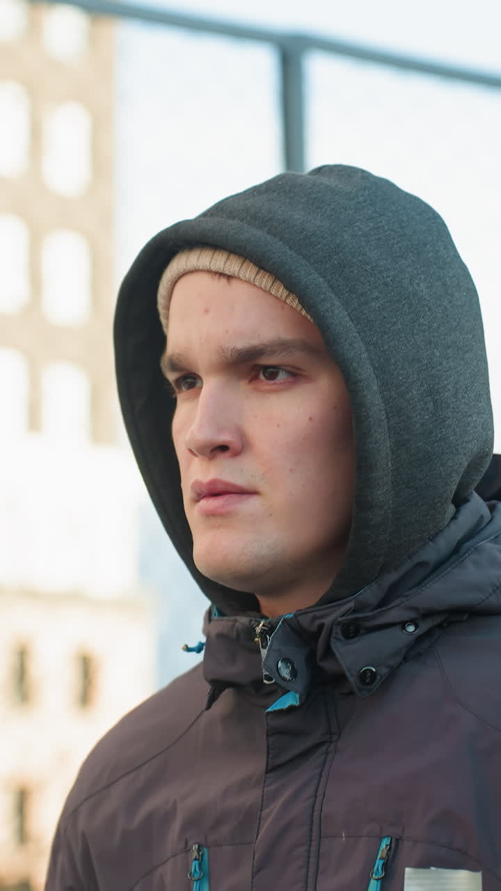 joven corriendo en una arena deportiva al aire libre con expresión enfocada, demostrando aptitud y acción, telón de fondo de edificio residencial y malla de alambre, con vista borrosa de la gente en el fondo
