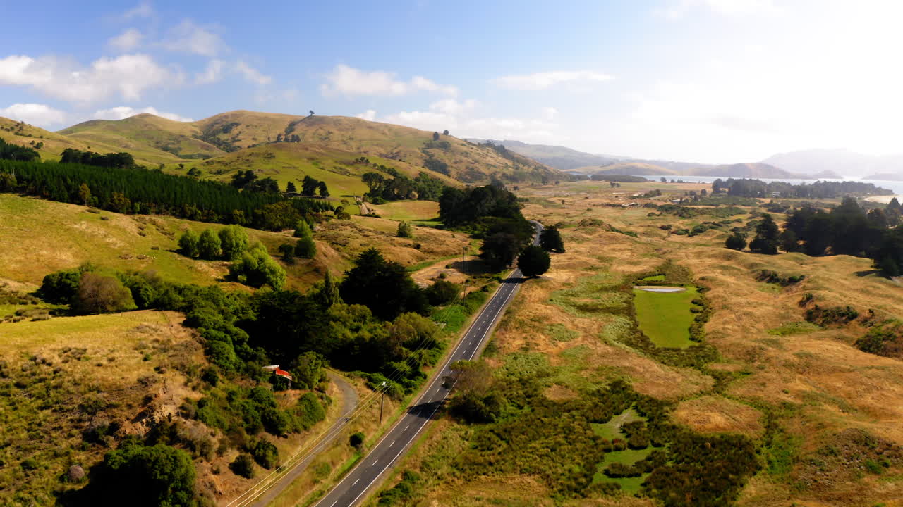 Aerial view of a scenic road winding through rolling hills and rural landscape