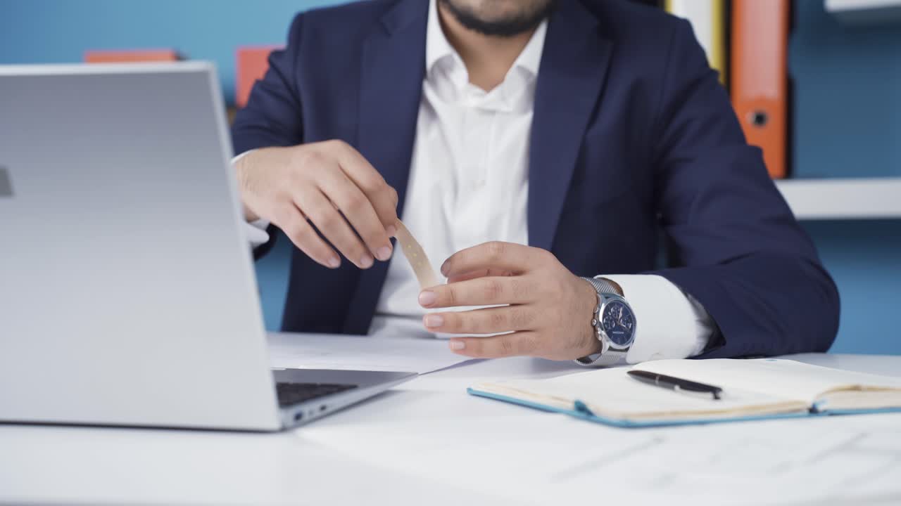 hombre de negocios metiendo una tirita en la oficina.