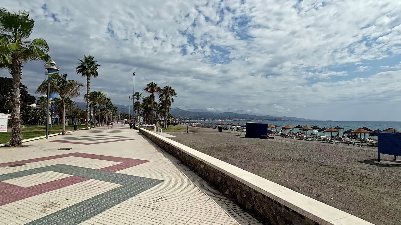 playa llena de turistas tomando el sol en un día nublado