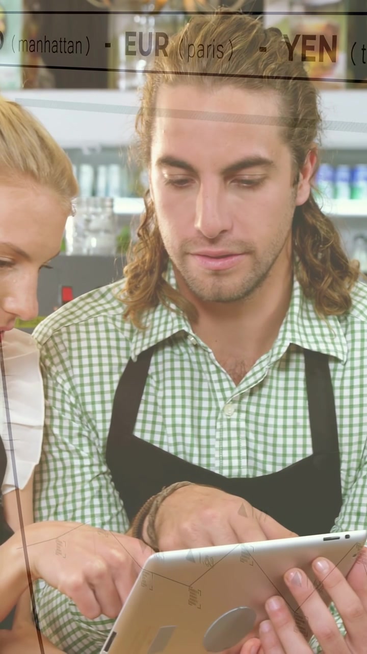 Vertikales Video: Barista tippt auf Tablet, USD EUR YEN Einblendung wird angezeigt, Frau kommt hinzu und aktualisiert Preise.