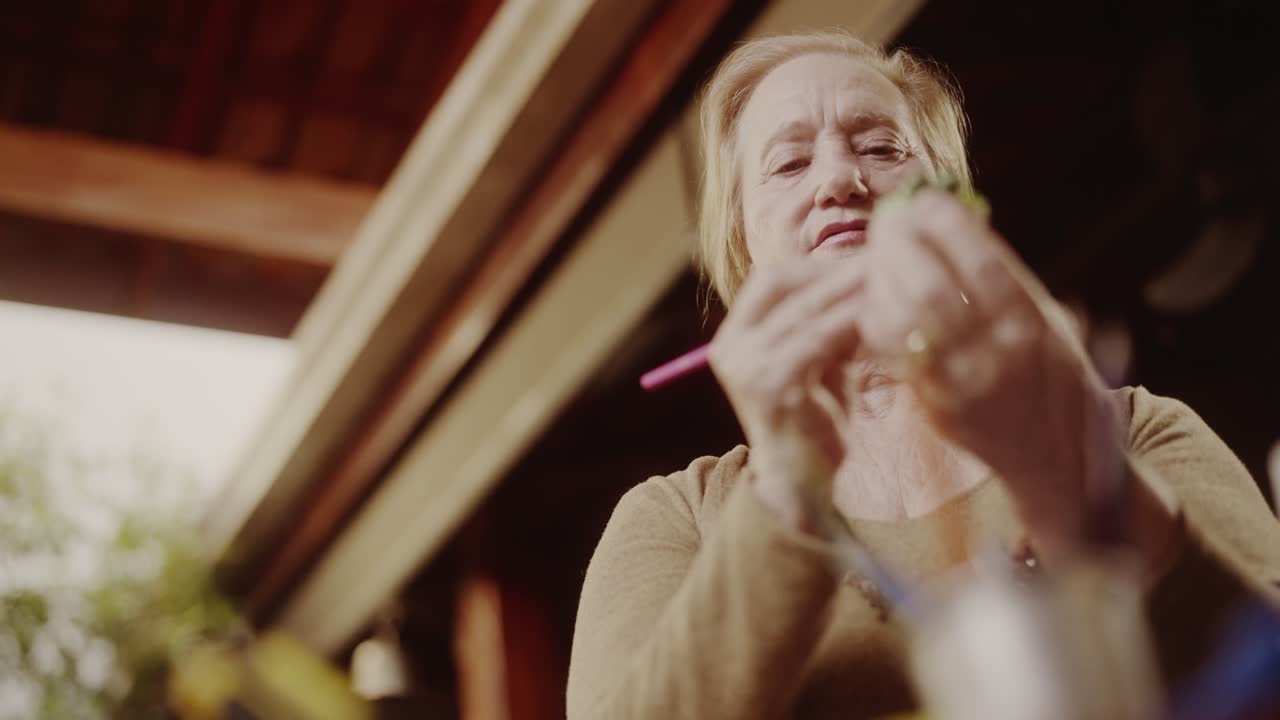 Elderly woman meticulously working on a small craft project