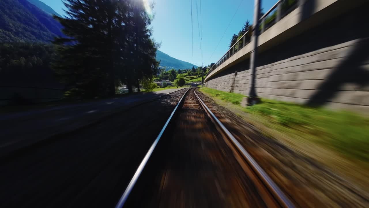 FPV drone races along railway tracks, then banks toward the lake, makes a quick turn and flies back to the railroad line