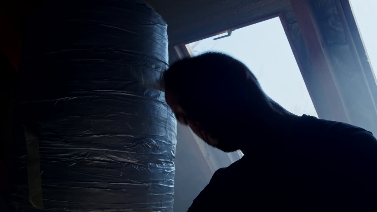 Man Training with Punching Bag in Attic