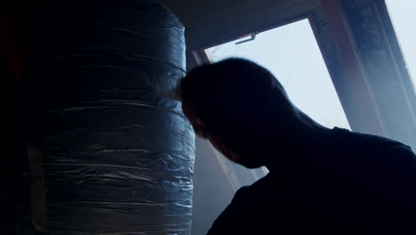 man training with punching bag in attic
