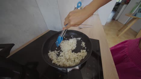 cooking rice in a frying pan on a stovetop
